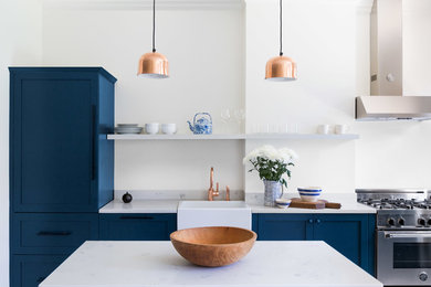 Trendy light wood floor and white floor eat-in kitchen photo in New York with a farmhouse sink, shaker cabinets, blue cabinets, quartzite countertops, stainless steel appliances and an island
