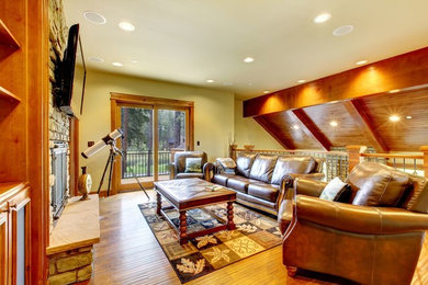Large mountain style open concept medium tone wood floor family room photo in Denver with beige walls, a standard fireplace, a stone fireplace and a wall-mounted tv