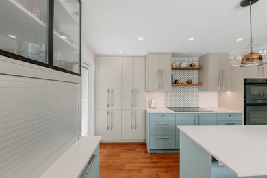 Inspiration for a mid-sized french country u-shaped medium tone wood floor and brown floor eat-in kitchen remodel in Montreal with an undermount sink, flat-panel cabinets, beige cabinets, tile countertops, multicolored backsplash, porcelain backsplash, paneled appliances, an island and beige countertops