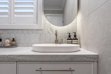 This is an example of a small master bathroom in Sydney with shaker cabinets, white cabinets, a corner shower, a one-piece toilet, gray tile, a drop-in sink, grey floor, a hinged shower door, grey benchtops, a niche, a single vanity and a floating vanity.