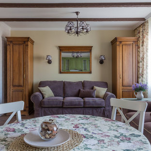 Ispirazione per un piccolo soggiorno country chiuso con pareti beige, pavimento in laminato, TV a parete e pavimento marrone