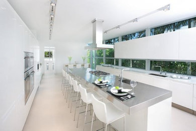 Example of a large minimalist marble floor kitchen design in Atlanta with granite countertops, stainless steel appliances, an island, flat-panel cabinets, white cabinets and an undermount sink