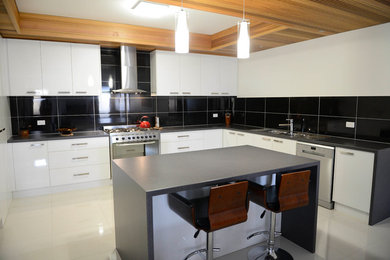 This is an example of a large modern u-shaped eat-in kitchen in Melbourne with with island, a double-bowl sink, flat-panel cabinets, white cabinets, laminate benchtops, grey splashback, glass tile splashback, white appliances and ceramic floors.
