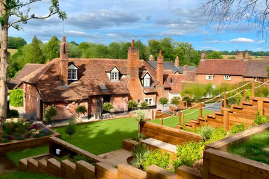 Photo of a large traditional back formal partial sun garden for summer in Hertfordshire with a retaining wall and a wood fence.