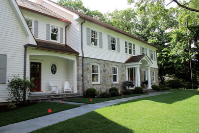 Large traditional white two-story stone exterior home idea in New York