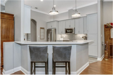 Open concept kitchen - galley gray floor open concept kitchen idea in Kansas City with shaker cabinets, gray cabinets, quartzite countertops, gray backsplash, porcelain backsplash, stainless steel appliances, a peninsula and white countertops