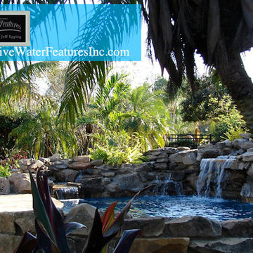 Tropical backyard room with pool waterfall, fireplace, and koi pond