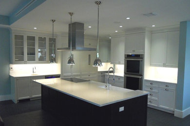 This is an example of a large contemporary l-shaped eat-in kitchen in Miami with recessed-panel cabinets, white cabinets, quartz benchtops, an undermount sink, white splashback, subway tile splashback, stainless steel appliances, with island and ceramic floors.