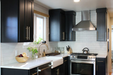 Inspiration for a small transitional l-shaped medium tone wood floor enclosed kitchen remodel in Kansas City with a farmhouse sink, shaker cabinets, black cabinets, quartz countertops, white backsplash, subway tile backsplash, stainless steel appliances, no island and white countertops