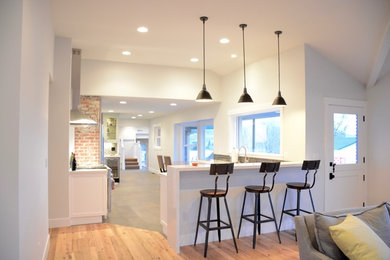 Example of a mid-sized farmhouse u-shaped slate floor eat-in kitchen design in Other with a farmhouse sink, shaker cabinets, white cabinets, marble countertops, gray backsplash, subway tile backsplash, stainless steel appliances and no island