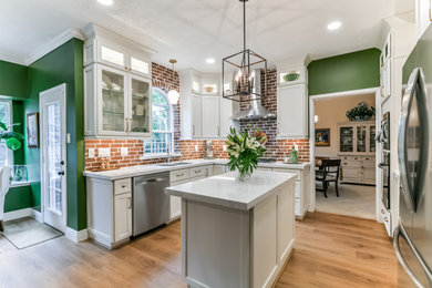 Eat-in kitchen - mid-sized l-shaped vinyl floor, brown floor and coffered ceiling eat-in kitchen idea in Houston with a double-bowl sink, raised-panel cabinets, white cabinets, quartzite countertops, brown backsplash, brick backsplash, stainless steel appliances, an island and white countertops