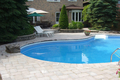 Example of a mid-sized backyard concrete paver pool design in Toronto