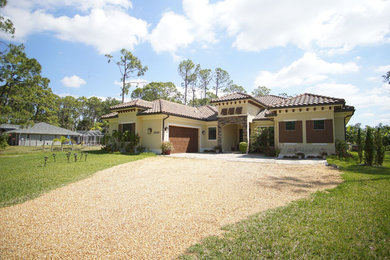 Inspiration for a large transitional brown one-story stucco house exterior remodel in Miami with a hip roof and a tile roof