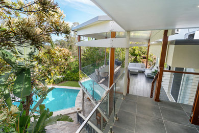 Backyard and first floor deck in Brisbane with glass railing.