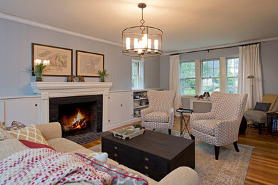 Design ideas for a mid-sized transitional enclosed living room in Boston with grey walls, light hardwood floors, a standard fireplace, a stone fireplace surround and no tv.