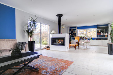 Large minimalist open concept travertine floor and beige floor living room library photo in Marseille with blue walls, a two-sided fireplace and a plaster fireplace