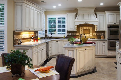 Eat-in kitchen - mid-sized traditional u-shaped ceramic tile eat-in kitchen idea in San Francisco with a double-bowl sink, beaded inset cabinets, white cabinets, granite countertops, beige backsplash, ceramic backsplash, stainless steel appliances and an island