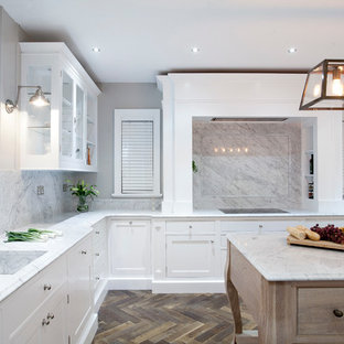 Large eclectic kitchen pantry photos - Large eclectic u-shaped dark wood floor kitchen pantry photo in Dublin with an undermount sink, beaded inset cabinets, white cabinets, marble countertops, white backsplash, stone slab backsplash, stainless steel appliances and an island