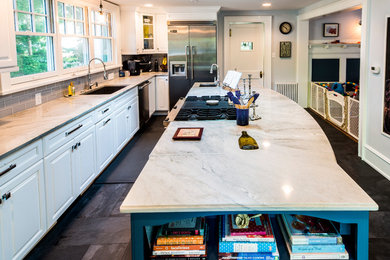Inspiration for a large craftsman l-shaped brown floor eat-in kitchen remodel in Philadelphia with white cabinets, gray backsplash, stainless steel appliances, an island, an undermount sink and raised-panel cabinets