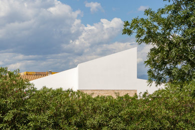 Imagen de fachada de casa blanca mediterránea de dos plantas con revestimientos combinados, tejado a dos aguas, tejado de teja de barro y escaleras