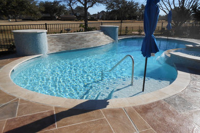 Inspiration for a large modern backyard stamped concrete and custom-shaped natural hot tub remodel in Houston