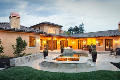 Patio fountain - huge mediterranean backyard stone patio fountain idea in San Francisco with a roof extension