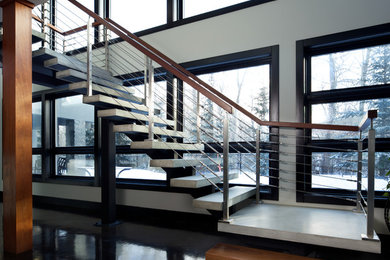 This is an example of a modern concrete floating staircase in Edmonton with open risers and cable railing.