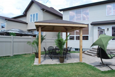Mid-sized transitional backyard stone patio photo in Ottawa with a pergola