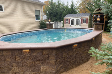 Photo of a large classic back custom shaped above ground swimming pool in New York with with pool landscaping and concrete paving.