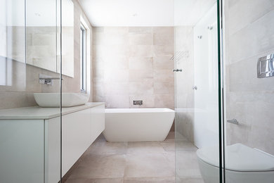 Mid-sized modern master bathroom in Sydney with raised-panel cabinets, white cabinets, a freestanding tub, an open shower, a one-piece toilet, gray tile, stone tile, grey walls, limestone floors, a drop-in sink, engineered quartz benchtops, grey floor, a hinged shower door and white benchtops.