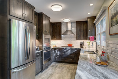 This is an example of a mid-sized transitional galley eat-in kitchen in Chicago with an undermount sink, beaded inset cabinets, dark wood cabinets, quartz benchtops, white splashback, subway tile splashback, stainless steel appliances, porcelain floors, no island, multi-coloured benchtop and grey floor.