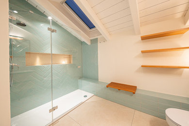 Mittelgroßes Modernes Duschbad mit flächenbündigen Schrankfronten, hellen Holzschränken, offener Dusche, Wandtoilette, Metrofliesen, weißer Wandfarbe, Keramikboden, Mineralwerkstoff-Waschtisch, beigem Boden, offener Dusche, weißer Waschtischplatte, Einzelwaschbecken, schwebendem Waschtisch und Einbauwaschbecken in München