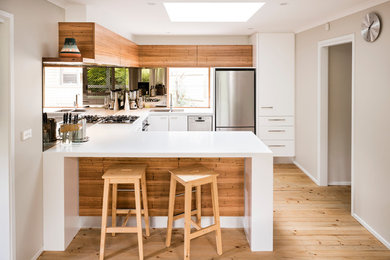 Inspiration for a small contemporary u-shaped eat-in kitchen in Melbourne with a double-bowl sink, white cabinets, solid surface benchtops, mirror splashback, stainless steel appliances and no island.