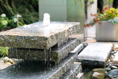This is an example of a mid-sized backyard stone water fountain landscape in Seattle.
