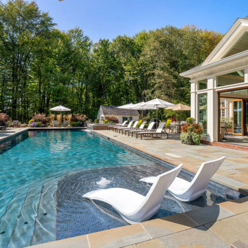 In-water loungers face the open glass cabana across the pool