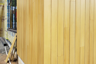 Imagen de fachada de casa actual grande de una planta con revestimiento de madera y tablilla