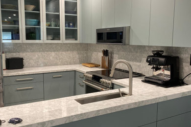 Example of a small trendy u-shaped dark wood floor and brown floor eat-in kitchen design in Toronto with an undermount sink, flat-panel cabinets, green cabinets, quartz countertops, green backsplash, quartz backsplash, stainless steel appliances and green countertops