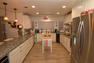 Large elegant u-shaped porcelain tile and brown floor open concept kitchen photo in Other with a farmhouse sink, recessed-panel cabinets, distressed cabinets, quartz countertops, beige backsplash, travertine backsplash, stainless steel appliances, an island and green countertops