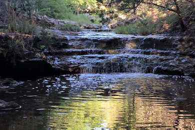 Inspiration for a large rustic partial sun backyard water fountain landscape in Austin.