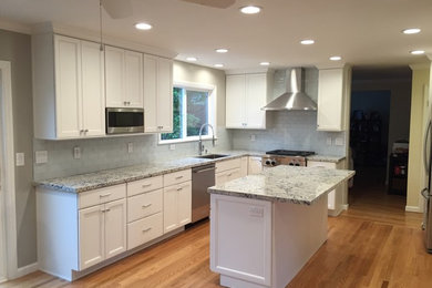 This is an example of a large contemporary kitchen in San Francisco with recessed-panel cabinets, white cabinets, granite benchtops, subway tile splashback, stainless steel appliances and with island.