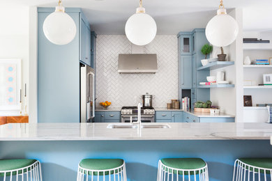 Inspiration for a transitional u-shaped kitchen in Chicago with an undermount sink, shaker cabinets, blue cabinets, white splashback, stainless steel appliances and with island.