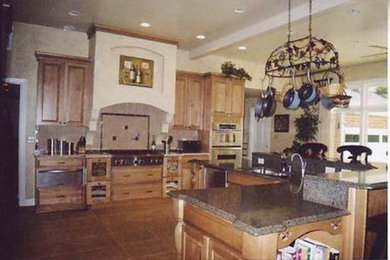 Large tuscan porcelain tile kitchen photo in Other with a drop-in sink, raised-panel cabinets, medium tone wood cabinets, granite countertops, stainless steel appliances and two islands