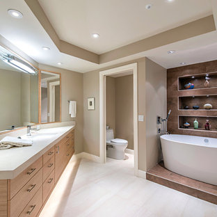 Freestanding bathtub - contemporary white floor freestanding bathtub idea in Atlanta with flat-panel cabinets, medium tone wood cabinets, a one-piece toilet, brown walls, an undermount sink and white countertops