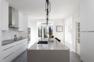 Large trendy porcelain tile and gray floor eat-in kitchen photo in Montreal with flat-panel cabinets, white cabinets, quartz countertops, white backsplash, an island and gray countertops