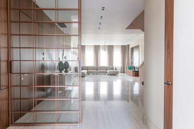 Стильный дизайн: большая гостиная комната в белых тонах с отделкой деревом в современном стиле с бежевыми стенами, полом из керамогранита и акцентной стеной - последний тренд
