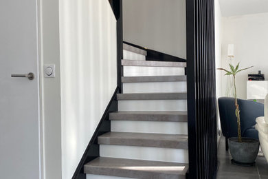 Cette image montre un escalier design en U de taille moyenne avec des marches en bois, des contremarches en bois, un garde-corps en câble, du papier peint et palier.