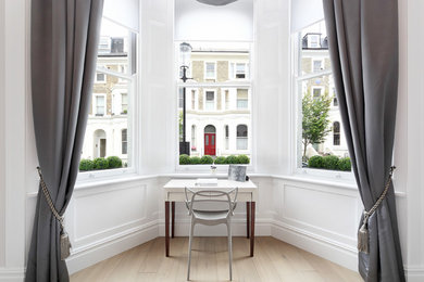 Photo of a mid-sized transitional home office in London with white walls, light hardwood floors and a freestanding desk.