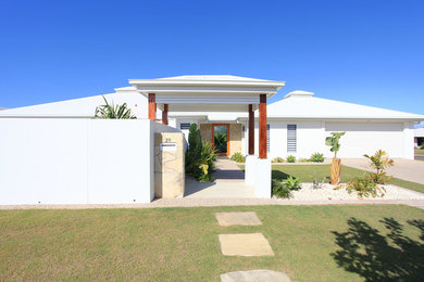 Photo of a contemporary white house exterior in Sunshine Coast with stone veneer and a metal roof.