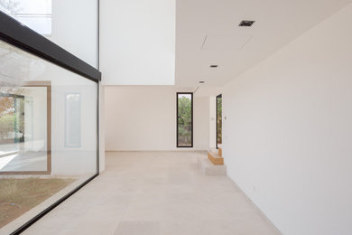 Foto de comedor minimalista grande abierto con paredes blancas, suelo de piedra caliza, suelo beige, bandeja y panelado