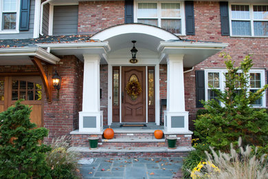 Mid-sized elegant red two-story brick exterior home photo in New York with a shingle roof